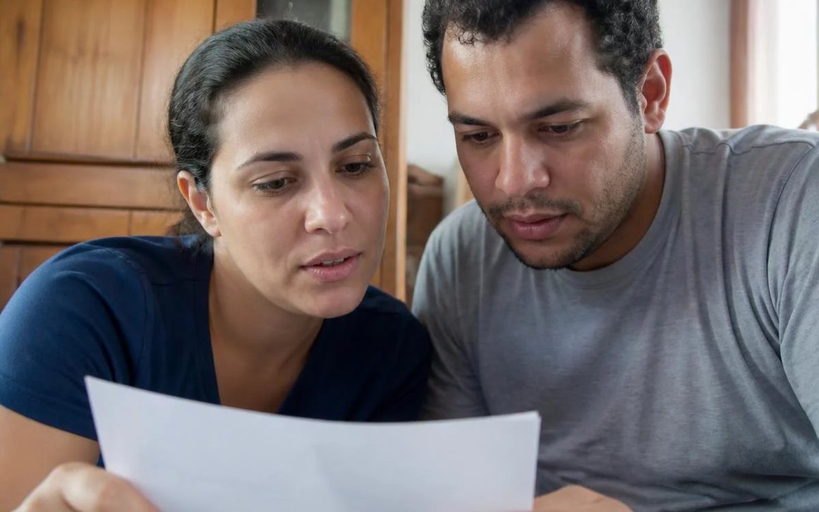 Duas pessoas frente a frente na mesa: uma sustenta a fala, a outra anota o que ouviu